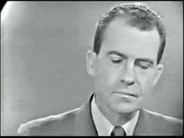 Political gif. Richard Nixon appears flustered and uncomfortable, as he nervously licks his lips and shifts his gaze away from us. He lets out a muffled sigh, trying to keep his composure.
