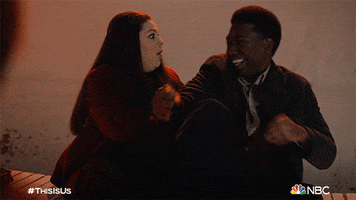 TV gif. Kate and Randall from This Is Us sit next to each other and fall over in glee, laughing with one another as they joke around.