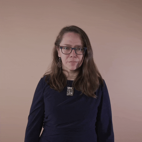 Reaction gif. A Disabled Latina woman with brown wavy hair and glasses makes a show of looking baffled, shaking her head, furrowing her brow, and dropping her hands in a gesture of questioning.