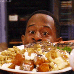 TV gif. Martin Lawrence from Martin peers longingly at a plate piled high with steak, potatoes, gravy, and vegetables with wide-eyed joy and anticipation. 