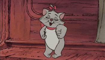 Disney gif. Marie the white kitten from The Aristocats, stands on her hind legs and dances on an upright, wood-toned piano. She looks happy and comfortable, with her eyes closed as she sings and dances. 