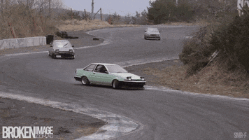 Sports gif. Continuous loop of a line of Toyota AE86 cars with their headlights up as they drift along a winding race track, one after the other