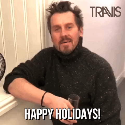 Video gif. Neil Primrose of the band Travis wears a turtleneck sweater and raises a glass, which sparkles. Text, "Happy holidays!"