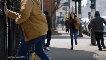 TV gif. A woman wearing a badge in Chicago PD runs down a city sidewalk with a badge hanging from her jeans as people around her run away in the opposite direction.