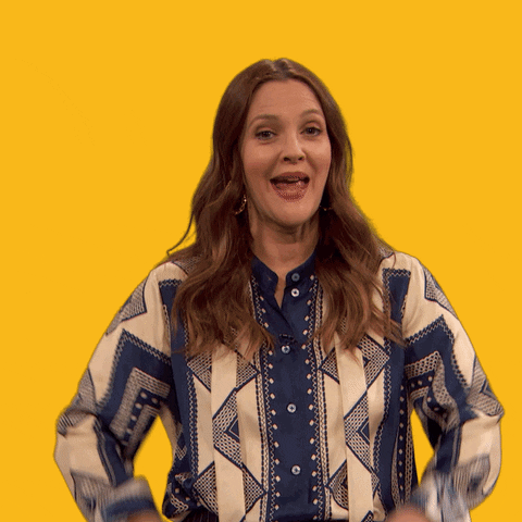 Celebrity gif. Drew Barrymore looks at us with a huge smile and lifts up two big thumbs up.