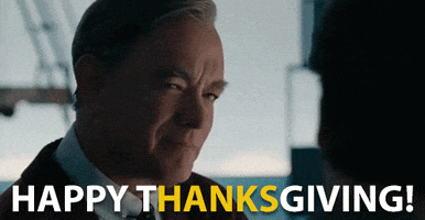 Movie gif. Tom Hanks as Fred Rogers in "A Beautiful Day in the Neighborhood" smiles subtly and blinks slow, looking at us. White text reads, "Happy Thanksgiving!" with the "Hanks" letters set off in yellow.