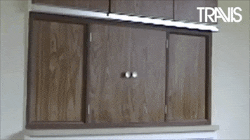 Video gif. We see a pair of small wooden doors covering a window between two rooms. The doors open, and a young man pops out with a smile. Text, "Happy New Year!"