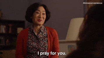 TV gif. Jean Yoon as Yong-mi Kim from Kim's Convenience bows slightly, a wry smile on her face, and says, "I will pray for you."