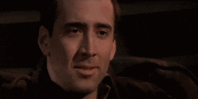 Movie gif. Nicholas Cage as Castor in Face Off rubs his face failing to suppress a chuckle and then bursts into laughter. 