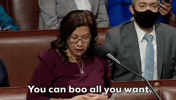 Political gif. Congresswoman Norma Torres stands in behind a microphone as she raises her hands as if indifference. Text, "You can boo all you want."