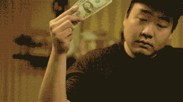 Video gif. David Cho, a Youtuber, is doing a shoulder dance and looks swaggy. He holds a one dollar bill in one hand and makes it rain, with one single dollar bill.