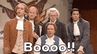 SNL gif. Four SNL cast members and Jason Sudeikis gather together, all dressed in colonial-era clothes and powdered wigs. One man yells, "Booo!" which appears as text, and the others join in.