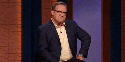 TV gif. Andy Richter on Conan. He sits with one hand on his hip and he glowers, taking a deep breath as a frown grows on his face.