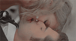 Music video gif. Taylor swift in the Blank Space music video is on top of a man in a suit and tie. His eyes are closed as she bites his lips sensually. 