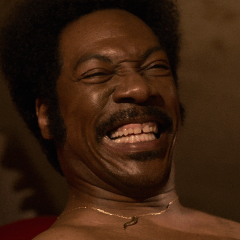 Movie gif. Eddie Murphy as Rudy in Dolemite gives a wide smile and shoots a finger gun at you.