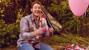 Sváteční gif s mužem v kárované košili vyhazujícím do vzduchu růžové okvětní lístky růží. 