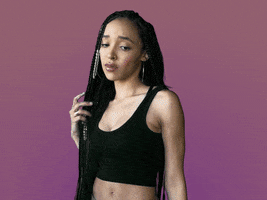 Celebrity gif. Tinashe twirls her waist-length hair, with braids in it, looking at us with a mild look of disgust, saying, "Ew."