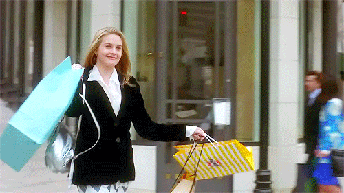 A gif of a woman walking out of shops with shopping bags.