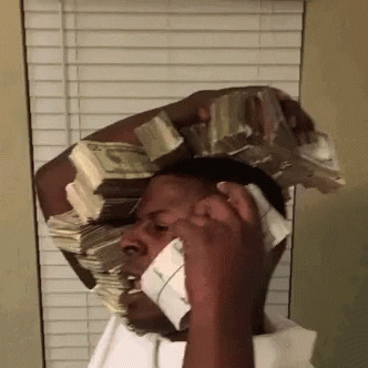 Video gif. A man holds a ridiculous amount of thick stacks of cash in his arms, trying to hold them all up to his ears like he’s talking on the phone. On one side of his head, the money stack goes from his shoulder all the way to the top of his head. On the other side he holds two stacks to his other ear. He paces around and pretends to talk into them.