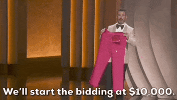 Oscars 2024 gif. Jimmy Kimmel wears a white blazer as he holds up a pair of Ryan Gosling's hot pink Ken pants for the crowd to take a gander. He says, "We'll start the bidding at $10,000."