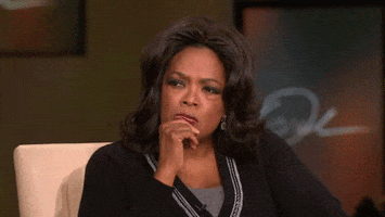TV gif. Oprah Winfrey has her hand on her chin and squints her eyes as she listens intently.