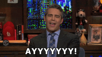 Celebrity gif. Andy Cohen has a smug grin on his face as he gives us two thumbs up, saying, "Ayyyyyyy!," which appears as text.