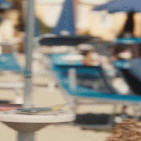 TV gif. Petra Nesvacilova in character is at the beach and is wearing a leopard print shirt and stylish brown sunglasses. Despite this, she squints upwards and scrunches up her nose in confusion. 