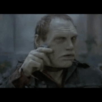 Movie gif. A creepy zombie in Day of the Dead scrapes the side of his face with a disposable razor, then looks down at the razor in his hand and licks his thumb.