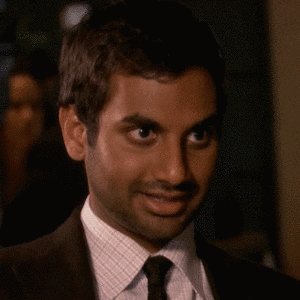 Parks and Recreation gif. Aziz Ansari as Tom looks to the side expectantly and then turns his face toward us with a big smiling grin.