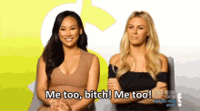 Video gif. Two women sit for an interview smiling, as one leans forward and, from the captions, enthusiastically says, "Me too, bitch! Me too!" The other girl laughs and holds her hand to her chest. 
