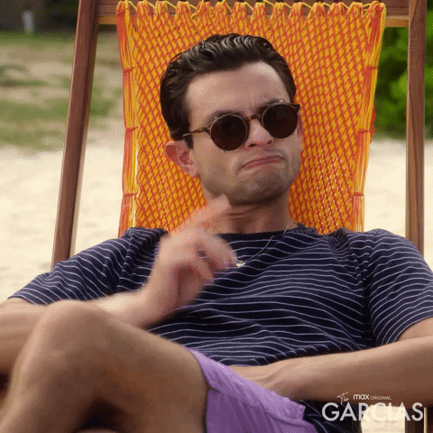 TV gif. Jeffrey Licon as Carlos in The Garcias. He's sitting in a beach chair and has shades on as he gives us a finger gun of acknowledgement and nods.