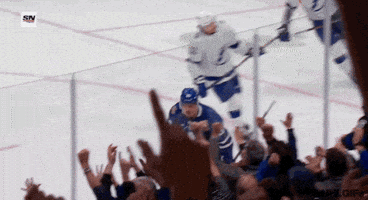 Sports gif. Auston Matthews from the Toronto Maple Leafs skates by the crowd and waves his hand up at them to rally their cheer with a roar. 