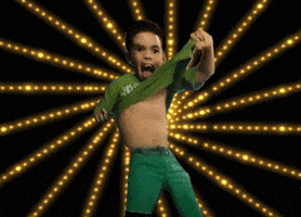 Video gif. A young boy gyrates and raises up his shirt with an open mouth as if yelling in celebration. Animated gold beams radiate from behind him. 