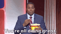 SNL gif. Wearing a dark blue suit, a smiling Kenan Thompson speaks to us as he snacks from a bucket of popcorn. Text, "You're all doing great."