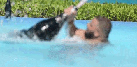 Gif s mužem v bazénu, který se snaží napít z obrovské láhve šampaňského.