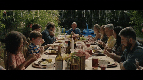 A long outdoor table where a whole family is eating the same meal together