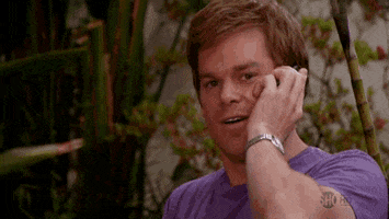 TV gif. Michael C Hall as Dexter holds a cellphone to his ear and looks at us with a half-smile, pointing his finger at us.