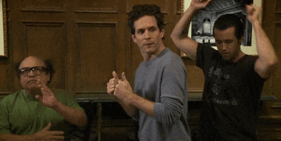 TV gif. Danny DeVito, Glenn Howerton, and Rob McElhenney as Frank, Dennis, and Mac on It's Always Sunny in Philadelphia celebrating by dancing.