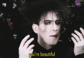 Celebrity gif. Robert Smith from The Cure gestures with both hands and says, “you’re beautiful.”