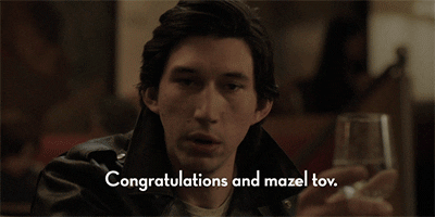 TV gif. Adam Driver as Adam Sackler on Girls holds a wine glass up in his hand and looks around as he says, “Congratulations and mazel tov.”