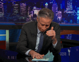 TV gif. Jon Stewart on The Daily Show. He claps his hands together and puts his head down, giving up.