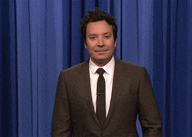Tonight Show gif. Standing in front of a blue curtain in a black suit, Jimmy Fallon looks around, points at himself, and asks: Text, "Me?"