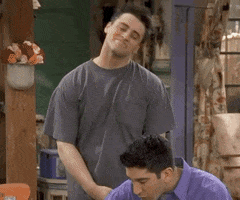 Friends gif. Matt LeBlanc as Joey leans over and hugs Ross, played by David Schwimmer, who is sitting at a table eating cereal.