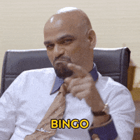 Video gif. Man sitting in office chair points and calmly says Bingo.