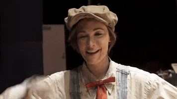 Music video gif. Behind the scenes for the Biscuits video, Kacey Musgraves, dressed like an old-time farmer in overalls, winks and tips her hat at us.