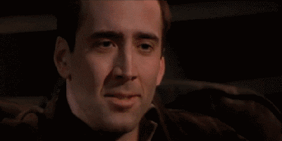 Movie gif. Nicolas Cage as Castor in Face Off covers his mouth as he stifles a smile before leaning forward as he erupts in laughter.