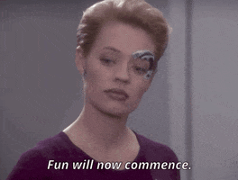 TV gif. Jeri Ryan as Seven of Nine in Star Trek Voyager turns robotically as she says the words that appear. Text, "Fun will now commence."
