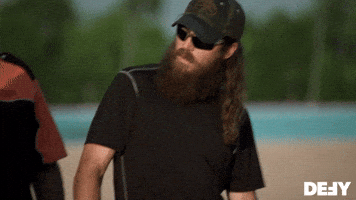 Reality TV gif. Jase Robertson on Duck Dynasty wears sunglasses as he looks at someone and then looks down, giving them a thumbs up.  