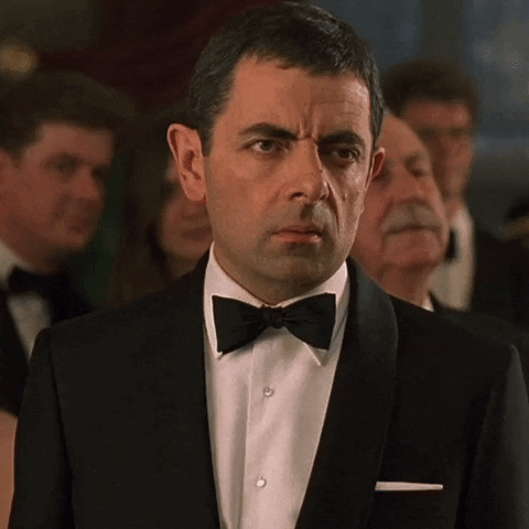 Movie gif. Rowan Atkinson as Johnny in Johnny English rolls his eyes as he looks to the side with disgust.