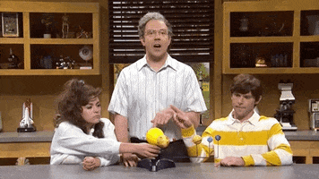 SNL Gif. Jason Sudeikis is dressed like a science teacher and smacks Cecily Strong’s and Mikey Day’s hands away from a model of the solar system.